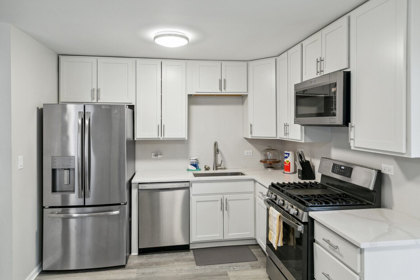 Una cocina moderna con electrodomésticos de acero inoxidable, armarios blancos y un microondas integrado.