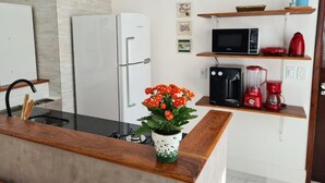 Eine moderne Küche mit Kühlschrank, Mikrowelle, Toaster und Kaffeemaschine auf Regalen.