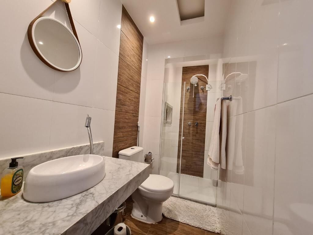 A modern bathroom with a marble sink, a toilet, and a glass-enclosed shower.