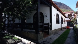 Ein Innenhof mit einem weißen Gebäude, einer hölzernen Bank und einem roten Stuhl.