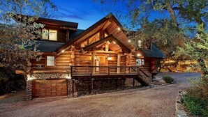 A log cabin with a stone foundation, a wooden deck, and a gravel driveway. - San Diego’s Luxury Mountain Cabin Retreat (El Cajon)
