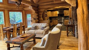 A log cabin interior with a dining area, sofas, a fireplace, and a kitchen. - San Diego’s Luxury Mountain Cabin Retreat (El Cajon)