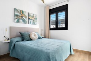 Une chambre à coucher avec un lit, une fenêtre et deux œuvres d’art accrochées au mur.