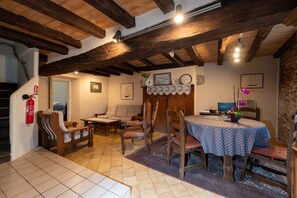 A rustic dining area with wooden furniture, a table with a patterned tablecloth, and a fire extinguisher on the wall.
