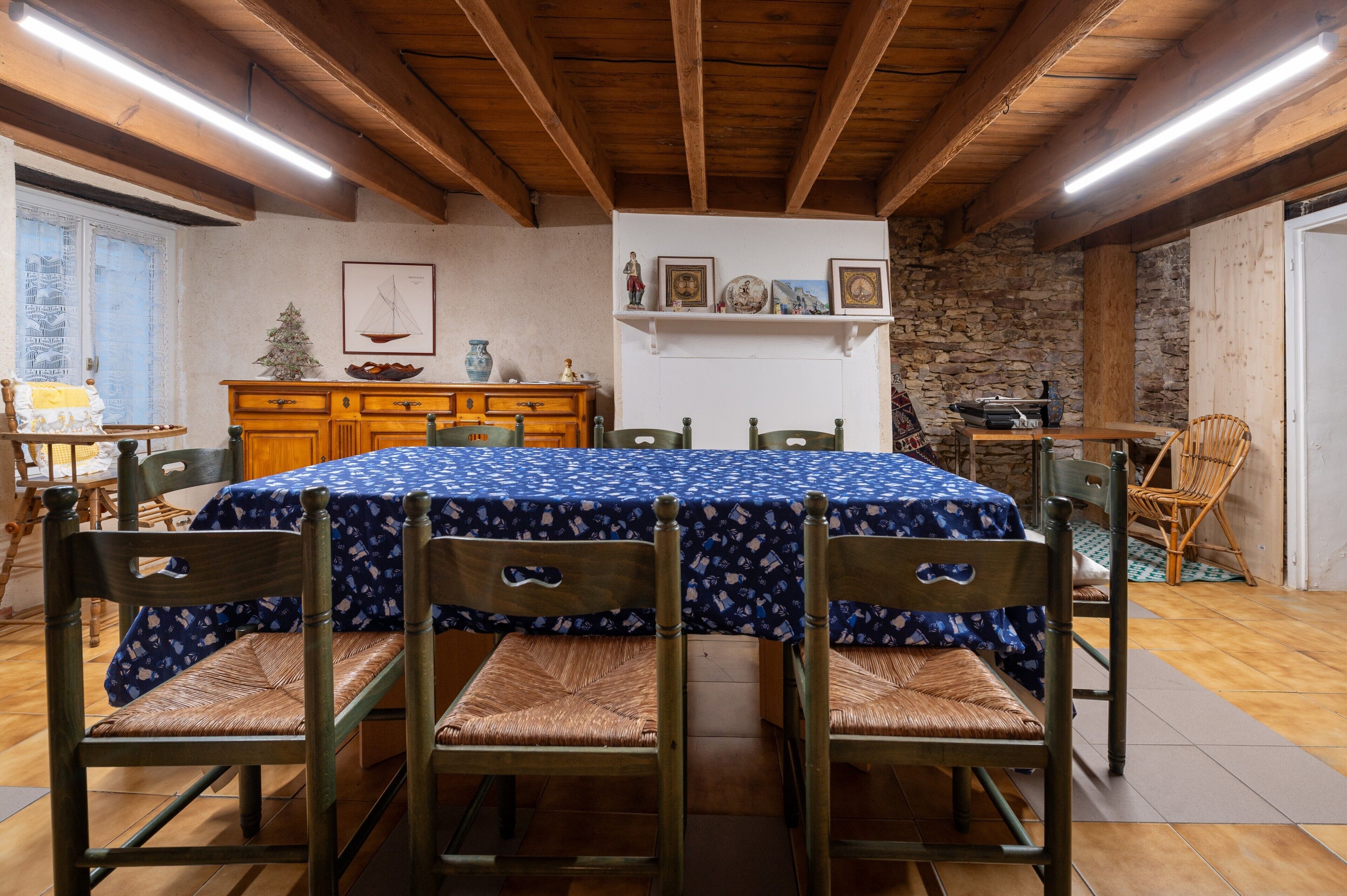 Un comedor con una mesa redonda cubierta con un mantel azul, rodeado de sillas de madera con asientos de mimbre.