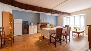 A dining area with a wooden table and chairs, a kitchen with a refrigerator and stove, and a large window.