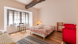 A bedroom with a bed, a chair, a small table, a red bed frame, and a window with curtains.