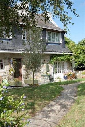 A stone house with a garden path leading to a patio area with outdoor furniture.