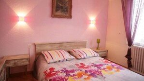 Een slaapkamer met een bed, twee nachtkastjes, een raam met gordijnen en een lijst met een foto aan de muur.