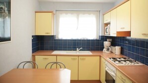 Een kleine keuken met een spoelbak, fornuis en kastjes.