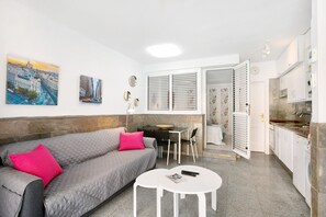 Un salon moderne comprenant un canapé, une table à manger et un coin cuisine.