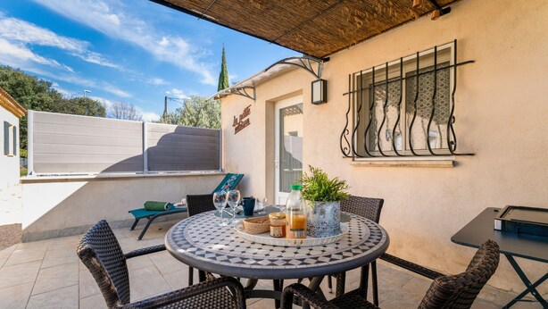 Eine Terrasse mit Korbstühlen, einem runden Tisch und einem Blumentopf.