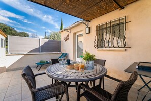 Une terrasse avec des chaises en osier, une table ronde et une plante en pot.