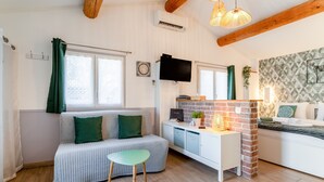 Ein gemütliches Wohnzimmer mit einer Couch, einem kleinen Tisch, einem Kamin aus Ziegelsteinen und einem Fernseher.