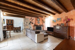 A cozy living room with a fireplace, wooden furniture, and stone walls.