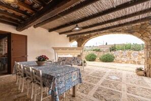 An outdoor patio with a stone table and chairs, a stone archway, and a view of the surrounding landscape.