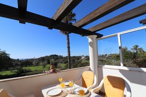 Un balcon avec une table dressée pour deux personnes, offrant une vue sur un paysage magnifique.