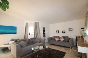 A modern living room with two grey sofas, a small coffee table, and a large abstract painting on the wall. - Villa 'La Perla' with Mountain View, Private Pool and Wi-Fi (Carvoeiro)
