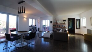 Un salon spacieux avec un coin repas, de grandes fenêtres et une cheminée.