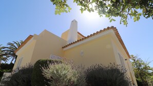 Ein Gebäude mit einem Ziegeldach, einem Schornstein und einem kleinen Garten mit Sträuchern und einer gemusterten Wand.