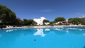 A clear blue pool with white lounge chairs and a white building in the background. - Apartment 'Casa Barbara' with Sea View, Shared Pool and Wi-Fi (Alporcinhos)