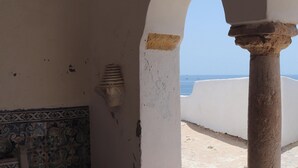 A room with a tiled bench, a wall with a decorative pattern, and a view of the sea through an archway. - Apartment 'Casa Barbara' with Sea View, Shared Pool and Wi-Fi (Alporcinhos)