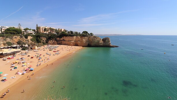 A beach with clear turquoise water, a sandy shore, and buildings on a cliff. - Apartment 'Casa Barbara' with Sea View, Shared Pool and Wi-Fi (Alporcinhos)