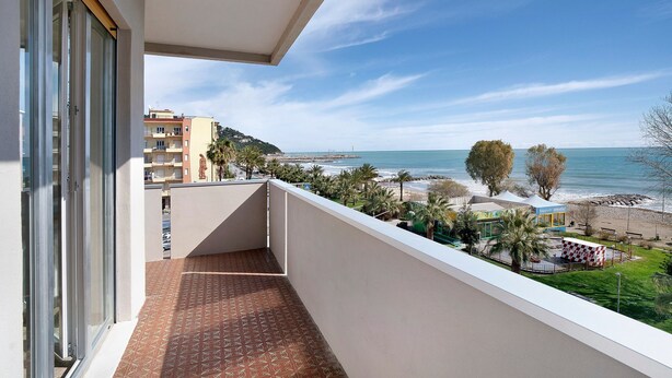 A balcony with a view of the beach and ocean, a tiled floor, and a building with a balcony. - Seafront Apartment 'Fronte Mare - Marina Di Andora' with Balcony, Wi-Fi & Air Conditioning (Marina di Andora)