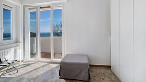 A room with a view to the sea, a sliding glass door, a small table, and a chair. - Seafront Apartment 'Fronte Mare - Marina Di Andora' with Balcony, Wi-Fi & Air Conditioning (Marina di Andora)