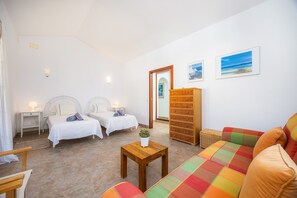 A hotel room with two beds, a sofa, a wooden table, and a large mirror.