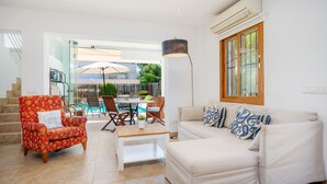 Ein Wohnzimmer mit einer Couch, einem Sessel, einem Couchtisch und einem Essbereich mit Stühlen und einem Tisch.