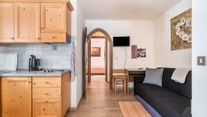 Una cucina compatta con mobili in legno, un piano cottura e una schiena a mosaico.