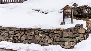 Un muro de piedra con un cartel de madera en un paisaje nevado.