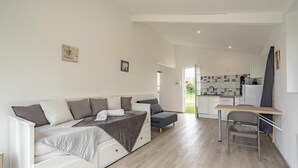 Una habitación moderna y bien iluminada con un sofá blanco, un escritorio pequeño y una silla.
