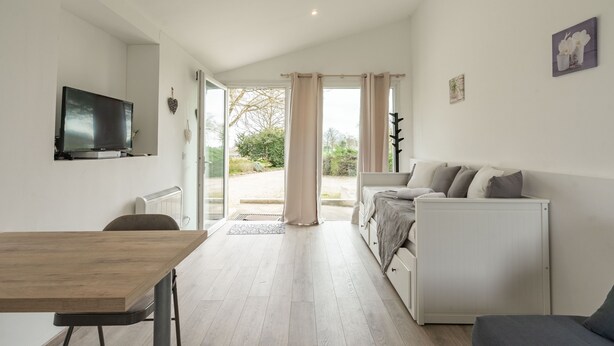Una sala moderna con televisor, sofá, mesa de comedor y área de cocina.