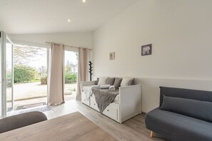 A modern room with a bed, a sofa, a dining table, and a view of the outdoors.