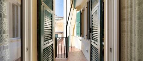 A narrow corridor with green shutters, a tiled floor, and a gate leading to an outdoor area.