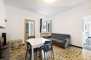 A compact living space with a dining table, a sofa, and a kitchenette area.