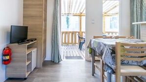 Een kamer met een televisie, een brandblusser, een houten bureau, een tafel met tafelkleed en uitzicht op het buitendek.