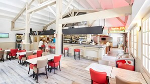 Een ruime eetzaal met hoge plafonds, een bar en uitzicht op het restaurant.