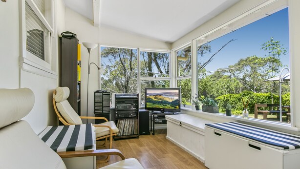 A cozy room with a large window, a television, and a seating area with a bench and chairs. - Experience Lavender Cottage, charming, cozy hideaway set in pretty bushland.  (Leura)