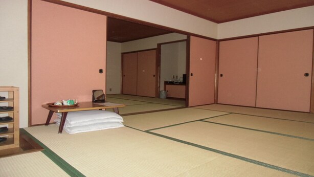 Una habitación japonesa tradicional con suelo de tatami, una mesa baja con cojín y puertas correderas.