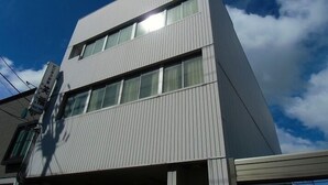 Un edificio moderno con techo plano y un amplio ventanal en el segundo piso.
