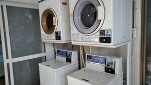 Un cuarto de lavandería con dos lavadoras y una secadora que funciona con monedas.
