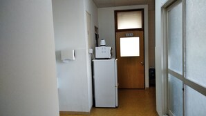 Un pasillo estrecho con un refrigerador blanco y una puerta con el símbolo de número.