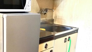 Una cucina compatta con frigorifero, lavello e forno a microonde.