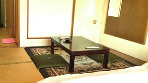 Una stanza con un letto, un tavolino con un telecomando, un tappetino e una porta.