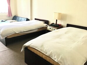 Two single beds with white linens, a bedside table with a lamp, and a telephone. - Hotel Sanda (Kobe)