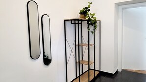A hallway with a black metal shelf unit with shelves and a potted plant on top. - Siccardsburggasse Apartment With 1 Balcony (Vienna)
