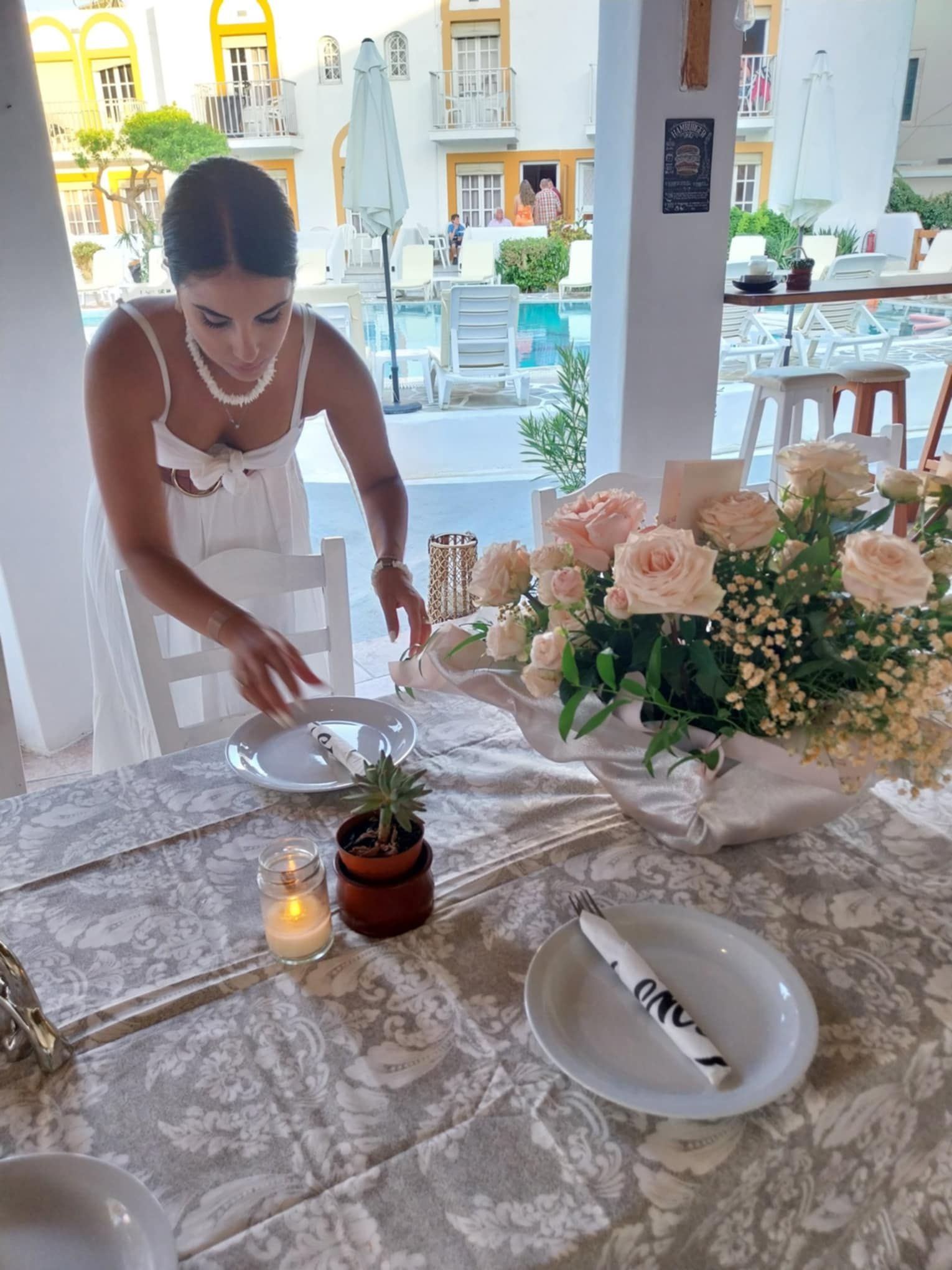 Una mesa dispuesta con un centro de mesa floral, una vela y un plato con servilleta.